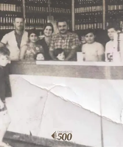 A família Ongarato reunida atrás do balcão do primeiro estabelecimento, em foto de época